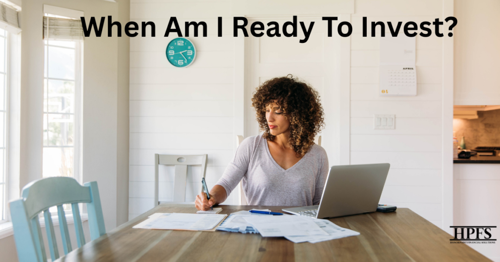 Woman budgeting at home to start investing, using a laptop, notebook, and calculator